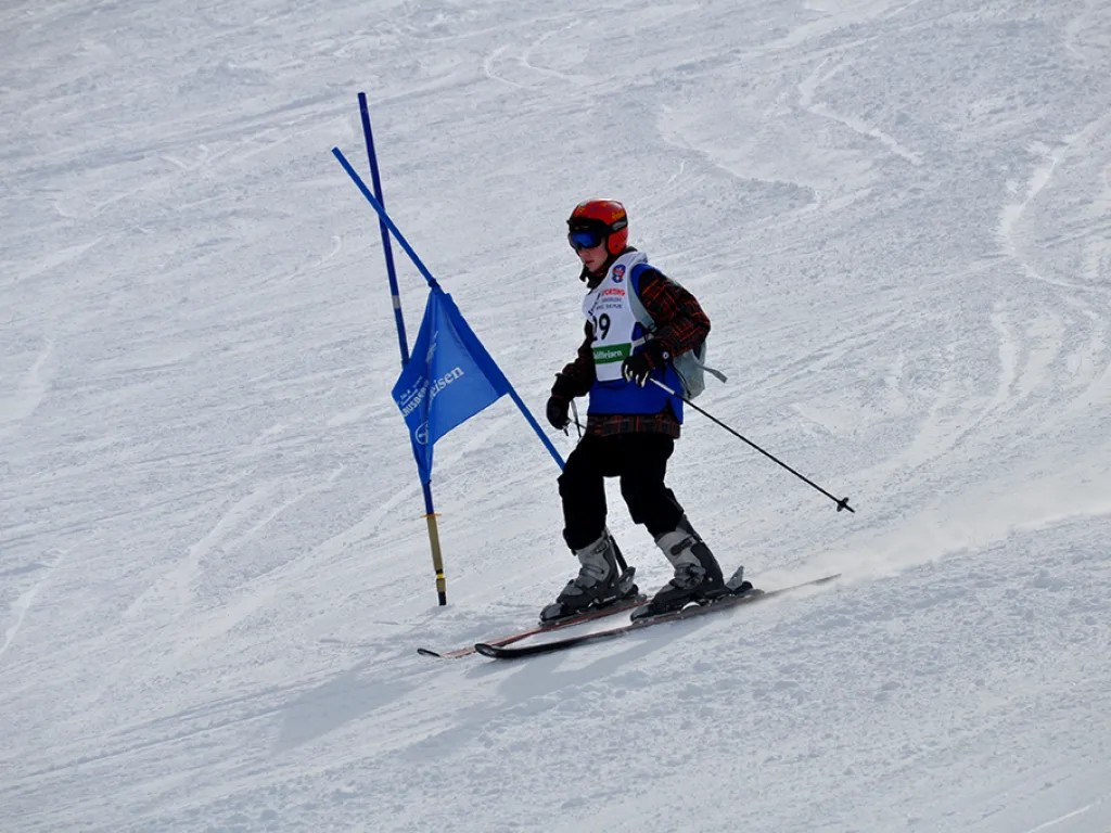 Skifahrer mit Rucksack passiert ein blaues Tor.